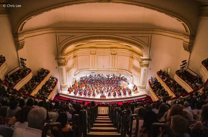 Orchestra performing on stage of the Carnegie Hall © Chris Lee