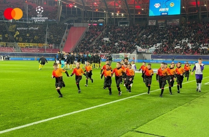 The children in the branded football uniforms running on a stadium.