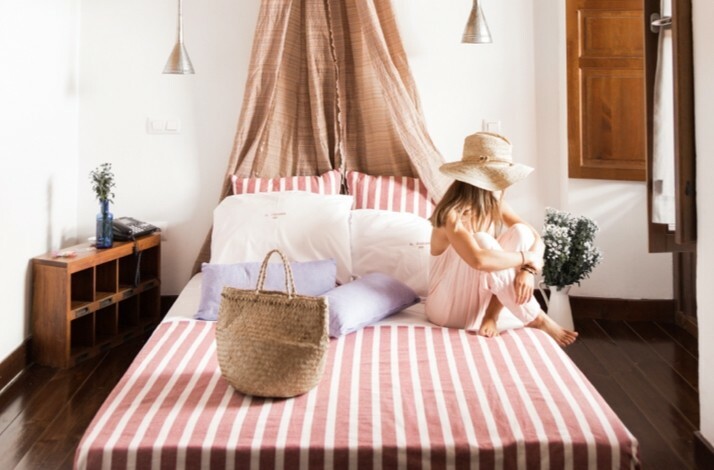 A person seated on a bed covered with pink linen at the Ruralka hotel.