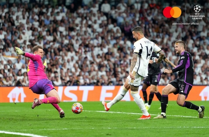 Football players during UEFA champions league match trying to kick the ball with the background of crowded audience.