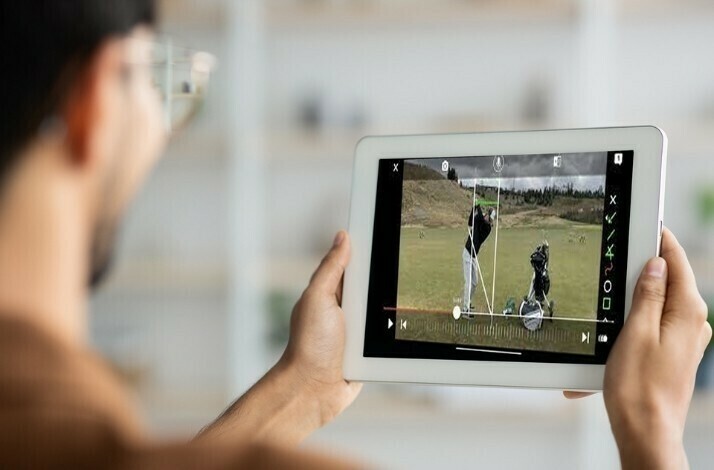 Young man watching the video on golf playing tips from a tablet