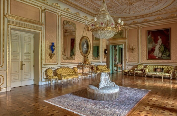 An elegant room in Palacio de Liria filled with antique furniture, detailed decorations, accentuated by framed pictures.