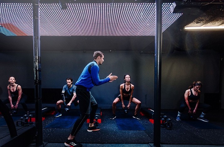 Shaped by iB coach Ivo in a gym with four gym-goers doing a kettlebell half squat position exercise.