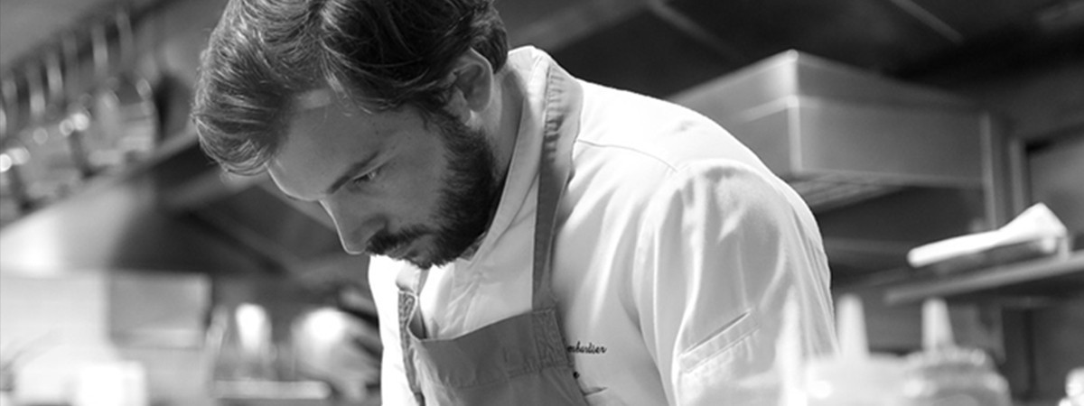 Black-and-white photo of chef Thibault Sombardier cooking at a restaurant’s kitchen.