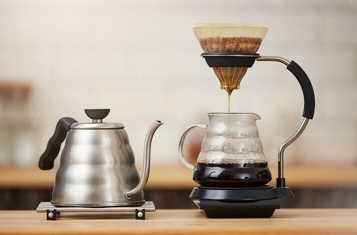 Coffee brewed by using a coffee cone and paper filter is dripping into a cup.