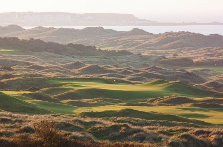 Bird's-eye view of Royal Portrush Golf course with a background of landscape. 