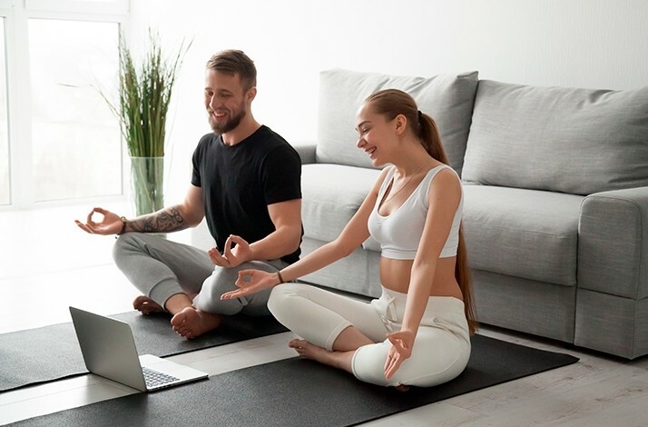 A man and a woman taking a relaxation pose during a webinar aimed at introducing wellbeing habits in compliance with practice of mindfulness.