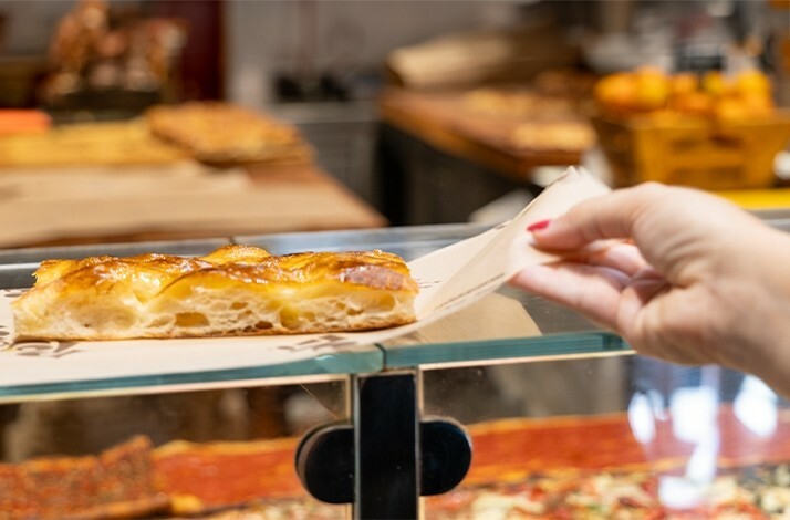 A woman grabbing a slice of pie from a stand.