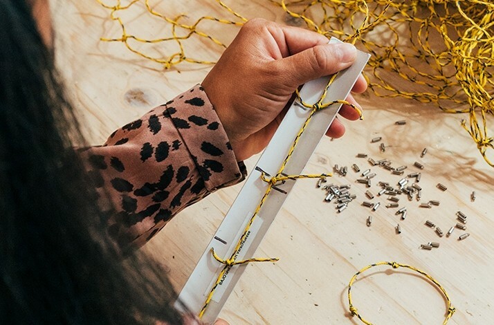 The woman is making a sustainable bracelet from the fishing net.