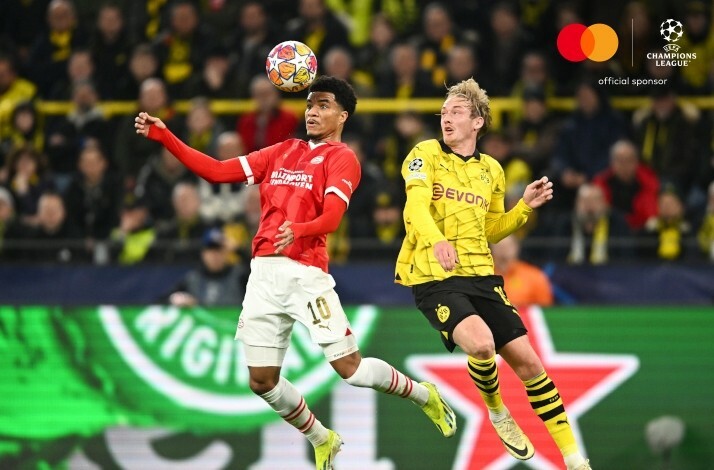 Two footballers during a match hitting the ball with head.